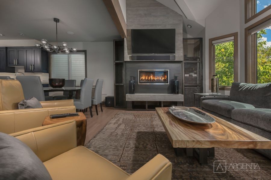 A home with an open floor plan, including a living room with a flat-screen TV over a soundbar and lit fireplace.