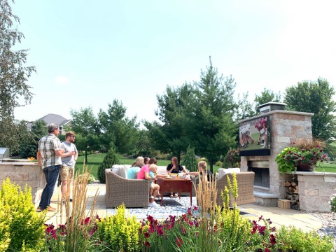 People gathered on an outdoor patio watching a football game on a Séura outdoor TV.