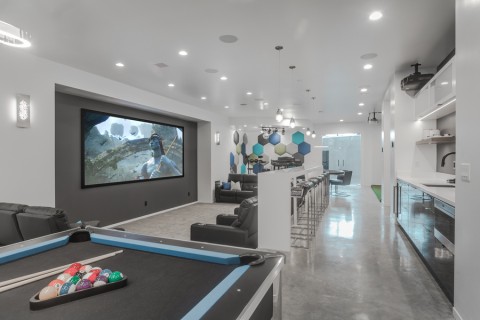 Modern home theater and gaming area with bartop seating behind the couch.