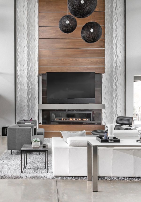 Sleek modern living room with wood-paneled fireplace, black pendant lights, and plush white seating