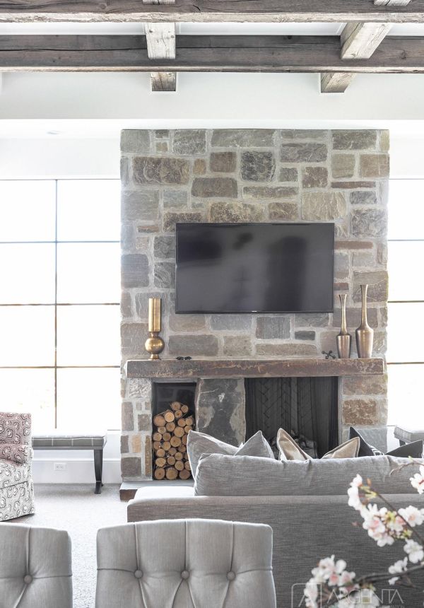 Cozy living room with stone fireplace, wood ceiling beams, and large grid windows