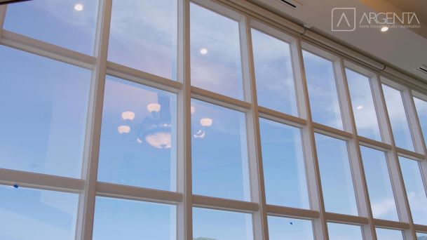 A large glass window reflecting the chandelier and a clear blue sky.