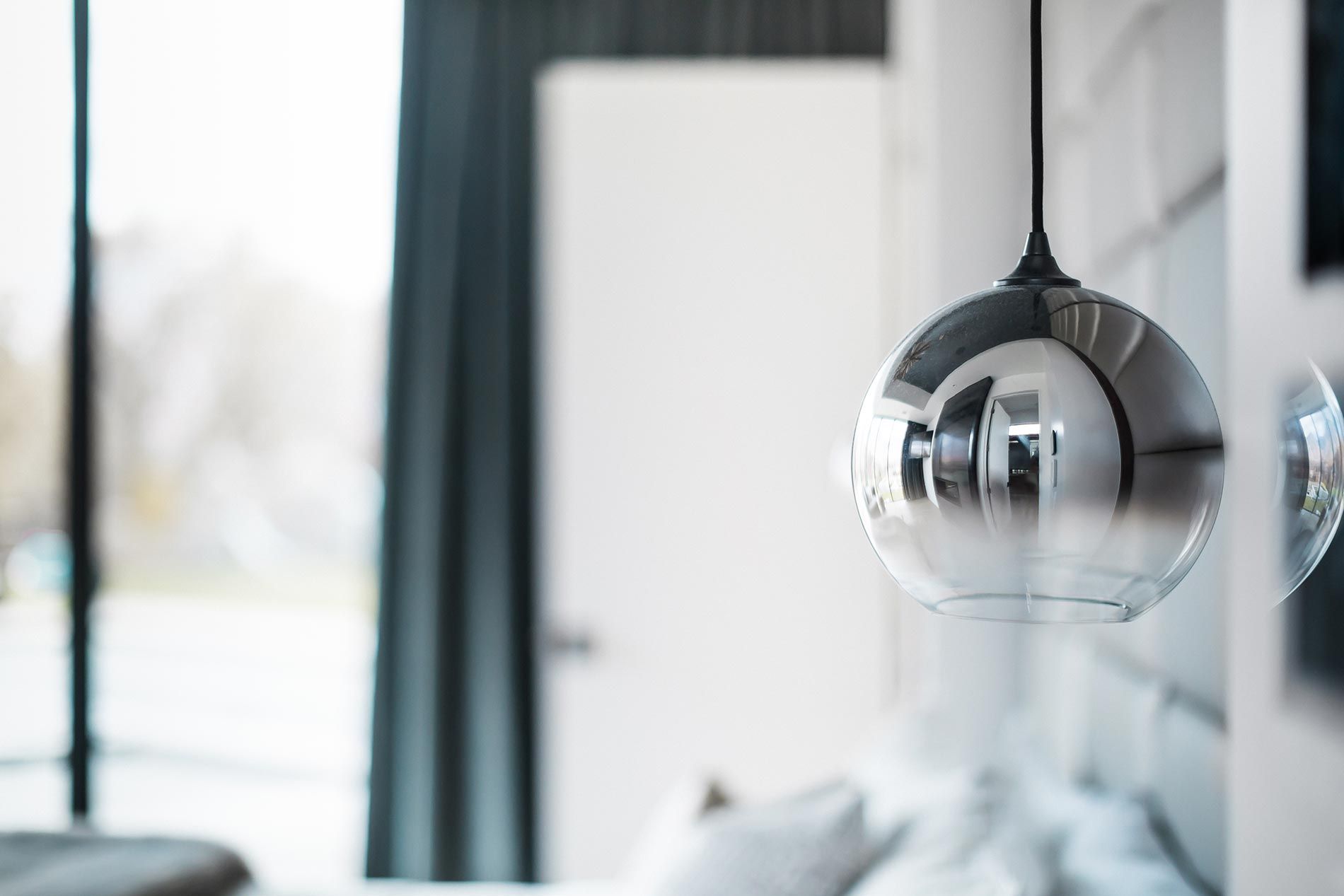 A close-up of a modern pendant light with a reflective glass design in a softly lit interior.