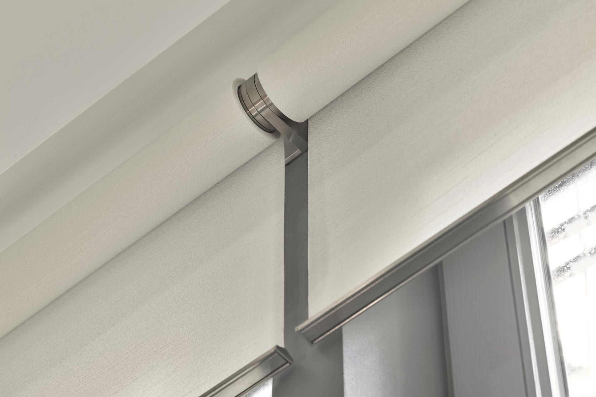 A detailed view of motorized window treatments with sleek, modern hardware in a bright, minimalist setting.